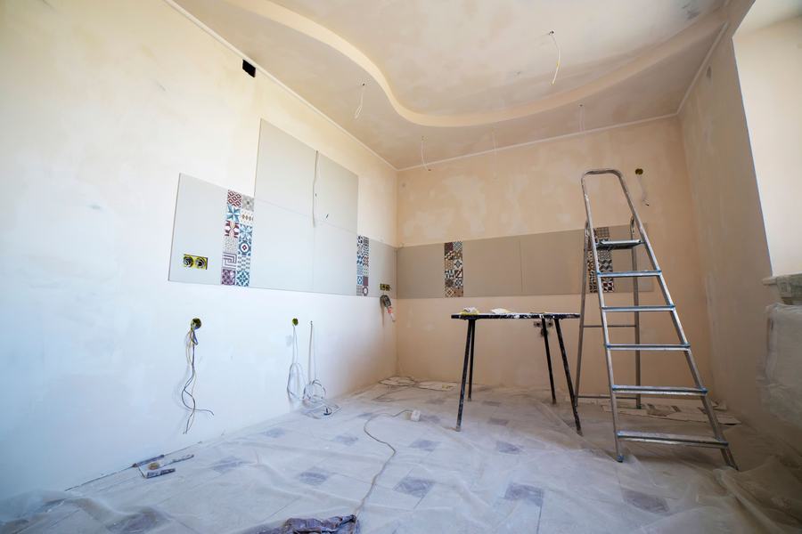Pièce en rénovation avec un faux plafond à courbe, une échelle et des sols protégés